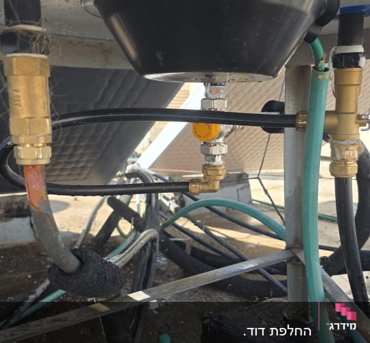 תקריב של חיבורי צנרת ושסתומים בתחתית דוד שמש על גג